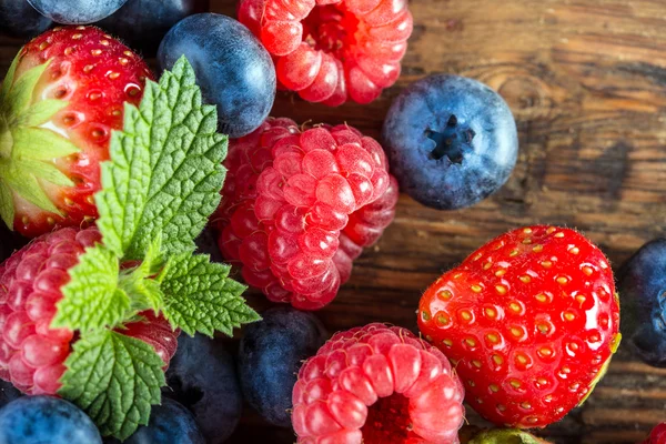 Berry frukter på trä bakgrund eller bord. blåbär, hallon, jordgubbar, skogen frukter. — Stockfoto