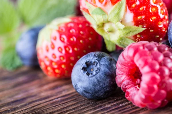 Berry frukter på trä bakgrund eller bord. blåbär, hallon, jordgubbar, skogen frukter. — Stockfoto