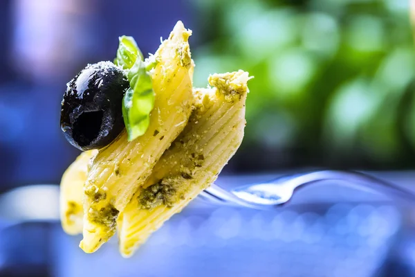 Servering av penne pasta på en gaffel med basilikablad och Svart oliv. — Stockfoto