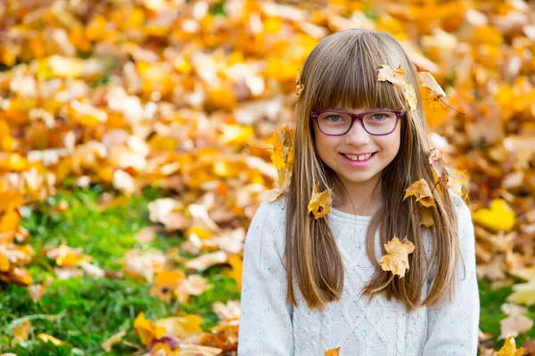 Retrato de uma jovem menina bonita que estava brincando alegremente com folhas de bordo de outono . — Fotografia de Stock