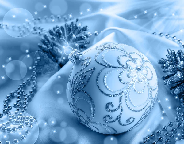 Kerstdecoratie. Kerstmis bal, dennenappels, glittery juwelen op wit satijn. — Stockfoto