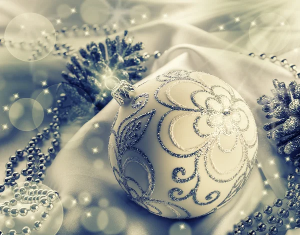 Christmas decoration. Christmas ball, pine cones, glittery jewels on white satin. — Stock Photo, Image