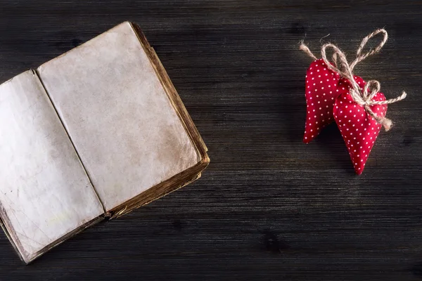 Día de San Valentín. Corazones hechos a mano de tela roja y viejo libro abierto sobre fondo de madera — Foto de Stock