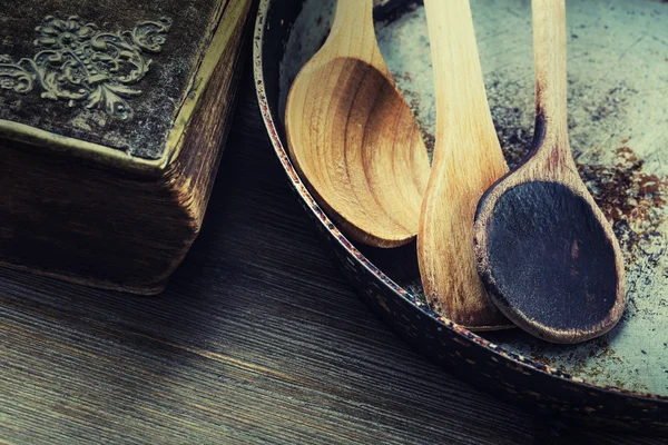 Utensílios de cozinha de madeira na mesa. Livro de receitas colher de madeira panela velha em um estilo retro na mesa de madeira — Fotografia de Stock