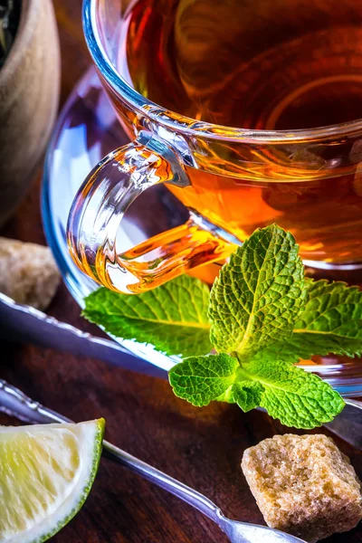 Thé dans une bouteille en verre, feuilles de menthe, thé séché, lime tranchée, sucre de canne — Photo