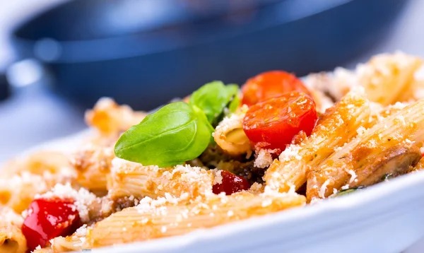 Pastas italianas con salsa de tomate y queso como decoración hojas de albahaca verde . — Foto de Stock