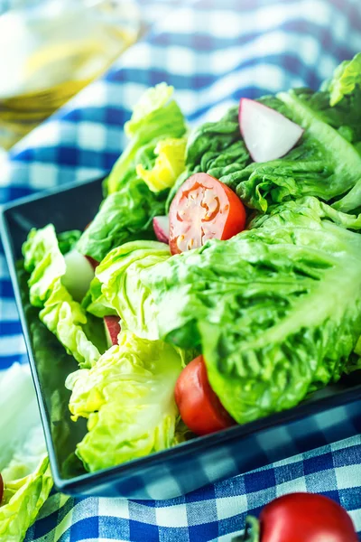 Frisk salatsalat med kirsebærtomater, reddik og karafe med olivenolje på trebord . – stockfoto