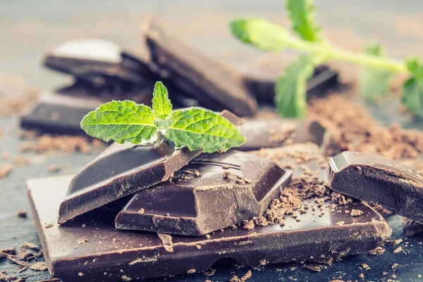 Chocolate. Black chocolate. A few cubes of black chocolate with mint leaves. — Stock Photo, Image