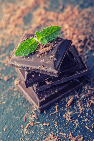 Chocolate. Black chocolate. A few cubes of black chocolate with mint leaves. — Stock Photo, Image