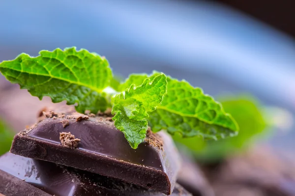 Chocolate. Black chocolate. A few cubes of black chocolate with mint leaves. — Stock Photo, Image