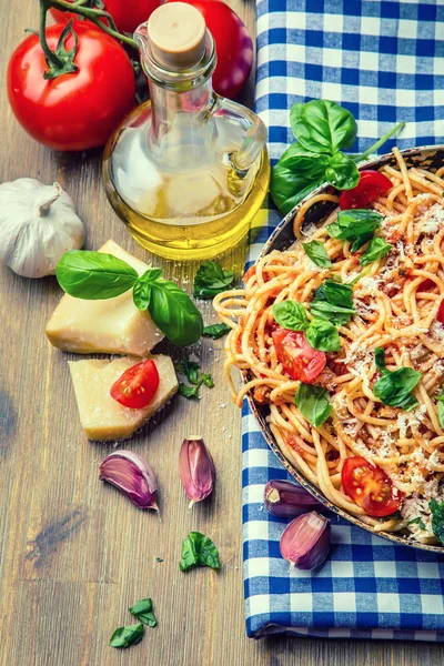 Bolonhesa de espaguete com tomate cereja e manjericão. Espaguete com molho de tomate na toalha de mesa quadriculada azul e mesa de madeira rústica — Fotografia de Stock