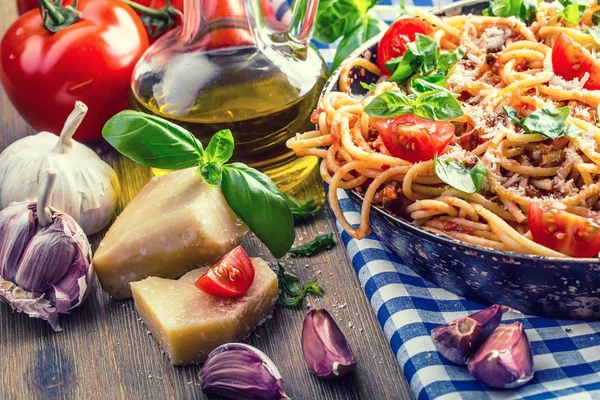 Spaghetti Bolognese mit Kirschtomaten und Basilikum. Spaghetti mit Tomatensauce auf blau karierter Tischdecke und rustikalem Holztisch — Stockfoto