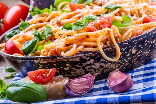 Spagetti bolognese kiraz domates ve fesleğen ile. Mavi kareli masa örtüsü ve rustik ahşap masa domates soslu spagetti — Stok fotoğraf