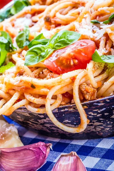 Espaguetis boloñés con tomate cherry y albahaca. Espaguetis con salsa de tomate sobre mantel a cuadros azul y mesa de madera rústica — Foto de Stock