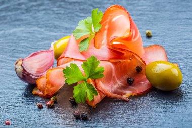 Kıvrılmış dilimleri, Delicious Prosciutto maydanoz ile granit tahta üzerinde yapraklar.