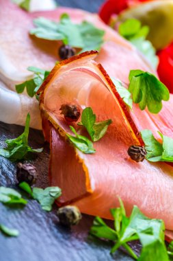 Kıvrılmış dilimleri, Delicious Prosciutto maydanoz ile granit tahta üzerinde yapraklar.