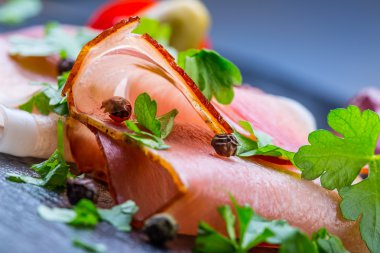 Kıvrılmış dilimleri, Delicious Prosciutto maydanoz ile granit tahta üzerinde yapraklar.