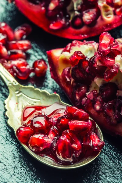 Trozos y granos de granada madura. Semillas de granada. Parte de la fruta de granada en el tablero de granito y cuchara antigua . — Foto de Stock