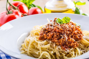 Spagetti. İtalyan ve Akdeniz mutfağı. Spagetti bolognese kiraz domates ve fesleğen ile. Mavi kareli masa örtüsü üzerinde domates soslu spagetti