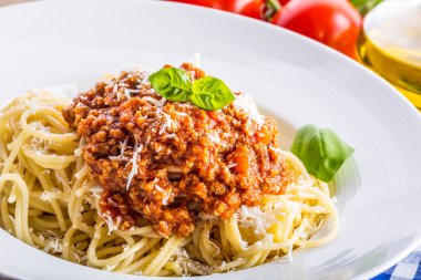 Spagetti. İtalyan ve Akdeniz mutfağı. Spagetti bolognese kiraz domates ve fesleğen ile. Mavi kareli masa örtüsü üzerinde domates soslu spagetti