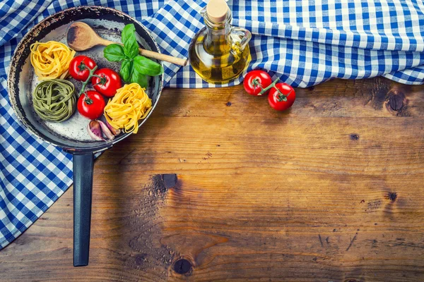 Italienska och medelhavsinspirerade livsmedelsingredienser på trä background.cherry tomater pasta, basilikablad och Karaff med olivolja. — Stockfoto