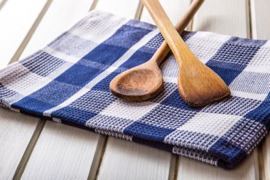 Two wooden cooking spoons on towel on wooden table.