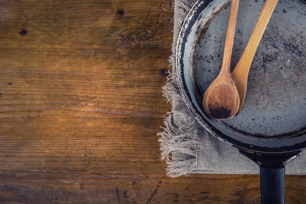 Wooden kitchen utensils on the table. Wooden spoon old pan in a retro style on wooden table. — Stockfoto