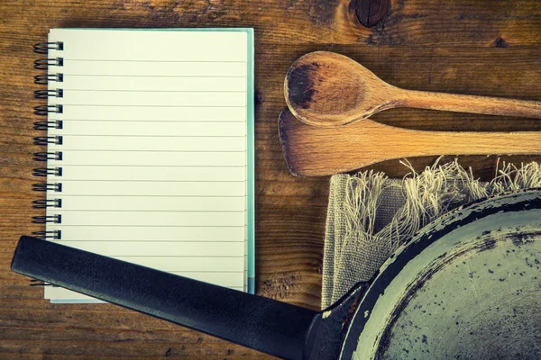 Utensilios de cocina de madera sobre la mesa. Libro de recetas cuchara de madera vieja sartén en un estilo retro en la mesa de madera . — Foto de Stock