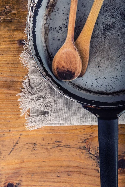 Wooden kitchen utensils on the table. Wooden spoon old pan in a retro style on wooden table. — Stock fotografie