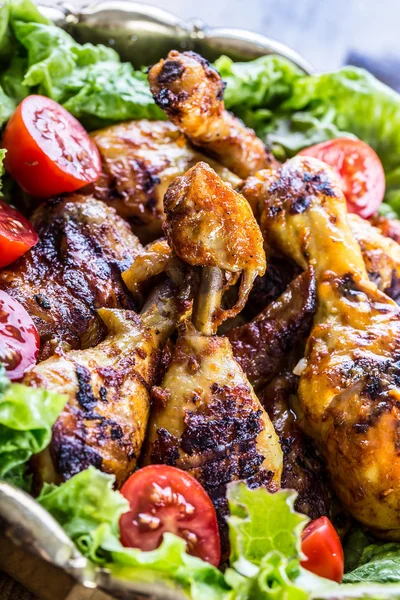 Grilling. Grilled chicken. Grilled chicken legs. Grilled chicken legs, lettuce and cherry tomatoes. Traditional cuisine. — Stock Photo, Image