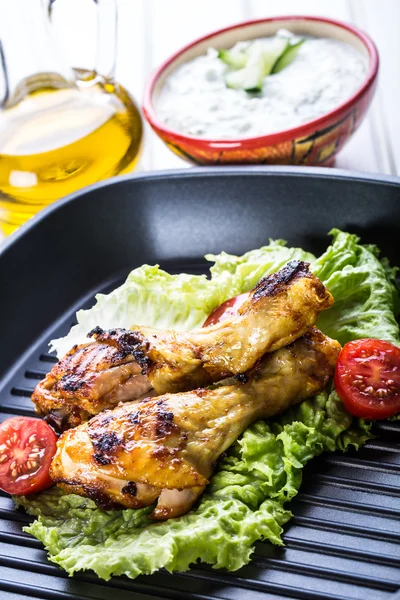 Grilling. Grilled chicken. Grilled chicken legs. Grilled chicken legs, lettuce and cherry tomatoes. Traditional cuisine. — Stock fotografie