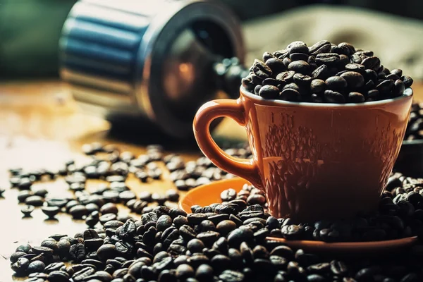 Café. Granos de café. Los granos de café asados se derraman libremente sobre una mesa de madera. Granos de café en un plato para café molido . — Foto de Stock