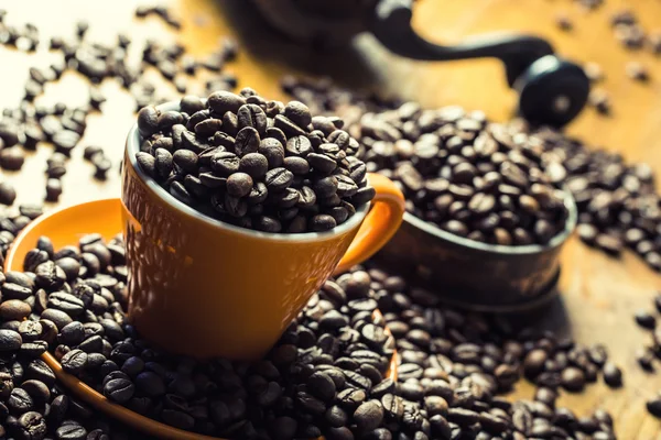 Café. Grãos de café. Grãos de café torrados derramados livremente em uma mesa de madeira. Grãos de café em um prato de café moído . — Fotografia de Stock