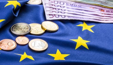 Greece and european  flag and euro money.  Coins and banknotes European currency freely laid on the European flag