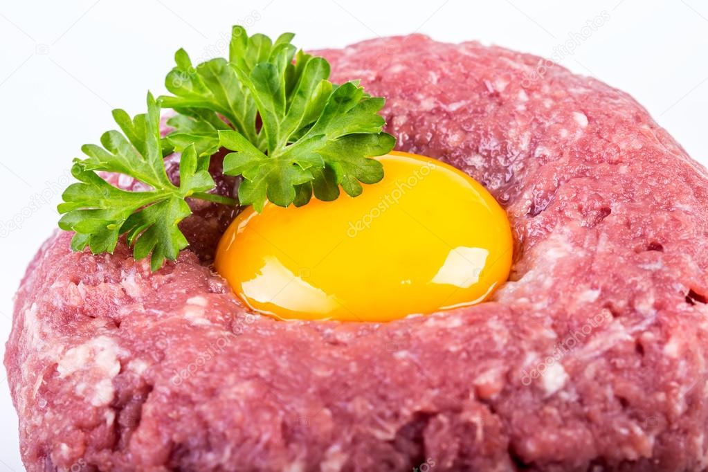 Tasty Steak tartare. Classic steak tartare over white. Ingredients: Raw beef meat salt pepper egg garlic chili herb decoration and toast bread. Isolated on white.