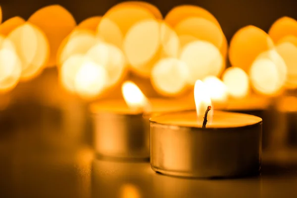 Golden light of candle flame. Christmas candles burning at night. Abstract candles background. — Stock Photo, Image