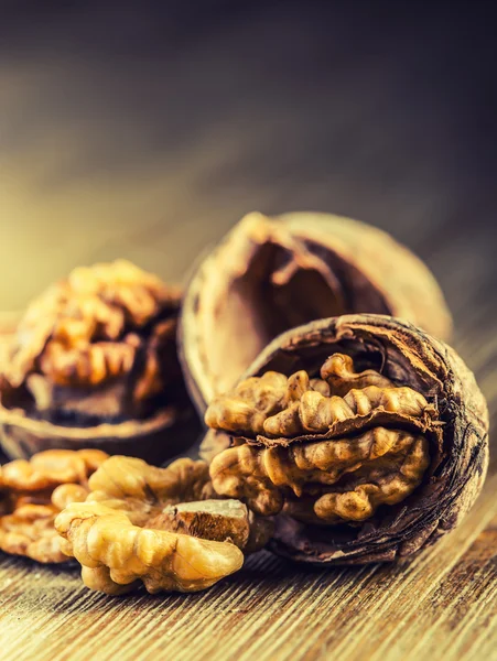 Nueces y nueces enteras sobre tabla de madera . — Foto de Stock