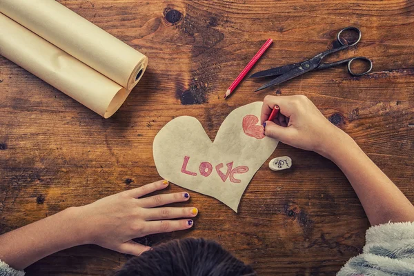 Młoda dziewczyna przyciąga miłość tekst na serca z papieru czerpanego. Valentines tekstu na papierze serca — Zdjęcie stockowe