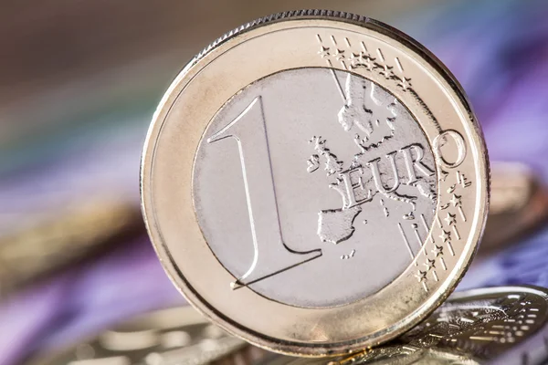 Several 500 euro banknotes and coins are adjacent. Symbolic photo for wealt.Euro coin balancing on stack with background of banknotes — Stock Photo, Image