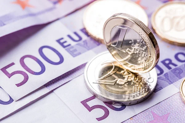 Verschillende 500 euro-bankbiljetten en -munten zijn naast. Symbolische foto voor wealt. Euromunt balanceren op stapel met achtergrond van bankbiljetten — Stockfoto