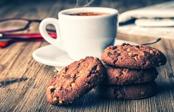 Cup of coffee with biscuit cookies and newspapper. Chocolate biscuit cookies. Chocolate cookies on white linen napkin on wooden table. Coffee break , breakfast — Stock Photo, Image