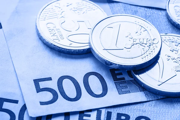 Verschillende 500 euro-bankbiljetten en -munten zijn naast. Symbolische foto voor wealt. Euromunt balanceren op stapel met achtergrond van bankbiljetten — Stockfoto