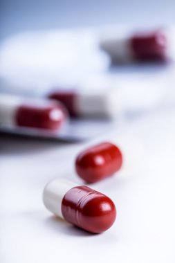 Pills. Tablets. Capsule. Heap of pills. Medical background. Close-up of pile of red white tablets - capsule. Pills and tablets.Blue background