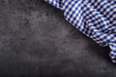 Top view of checkered kitchen tablecloth on granite -  concrete - stone background. Free space for your text or products