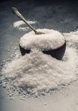 Salt. Coarse grained sea salt on granite - concrete  stone background with vintage spoon and wooden bowl