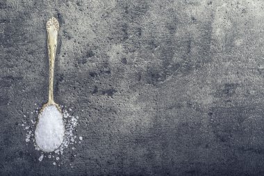 Salt. Coarse grained sea salt on granite - concrete  stone background with vintage spoon and wooden bowl