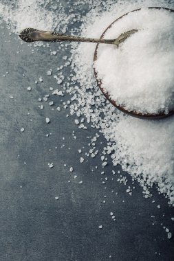 Salt. Coarse grained sea salt on granite - concrete  stone background with vintage spoon and wooden bowl