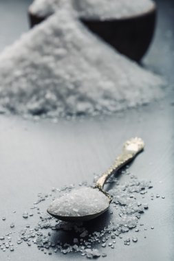 Salt. Coarse grained sea salt on granite - concrete  stone background with vintage spoon and wooden bowl