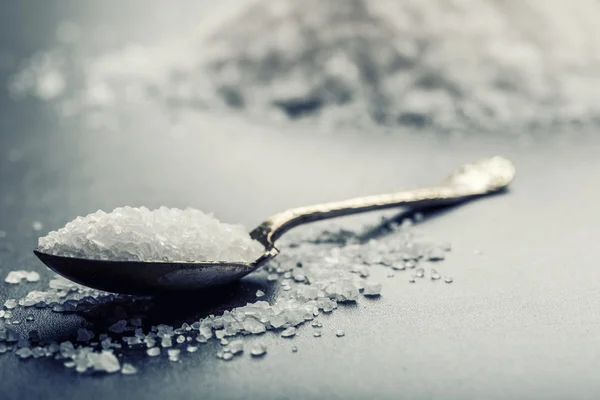 Salt. Coarse grained sea salt on granite - concrete  stone background with vintage spoon and wooden bowl — Stockfoto