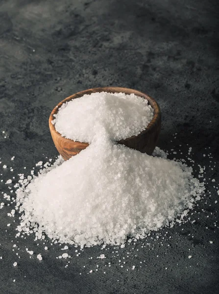 Salt. Coarse grained sea salt on granite - concrete  stone background with vintage spoon and wooden bowl — ストック写真